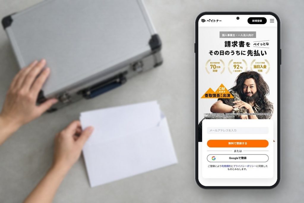 撮影機材の横で請求関連書類を封筒に収める手元